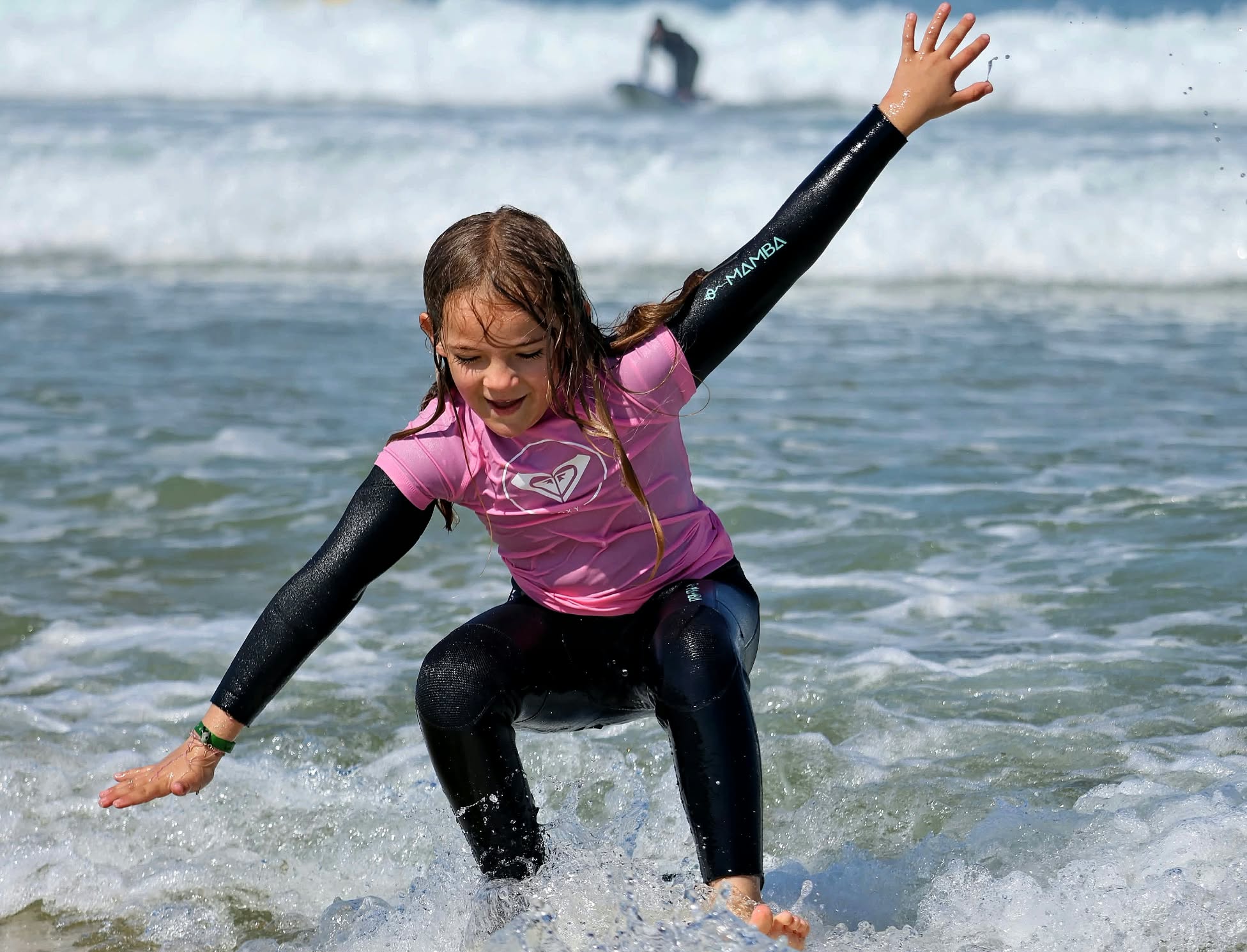 Jeune surfeuse en rose trouvant son équilibre dans l'écume